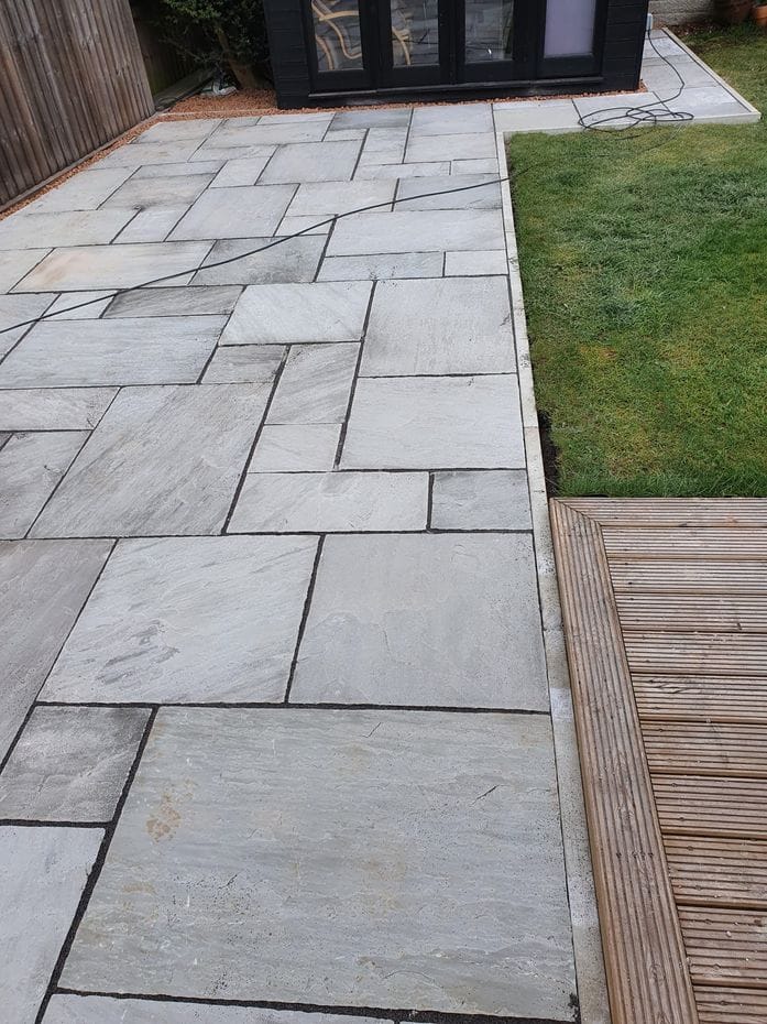 Grey sandstone paving laid next to lawn and garden room